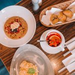 Porridge garniert mit Granatapfel und Bananenscheiben, samt einen mit Orange garnierten Früchtetee